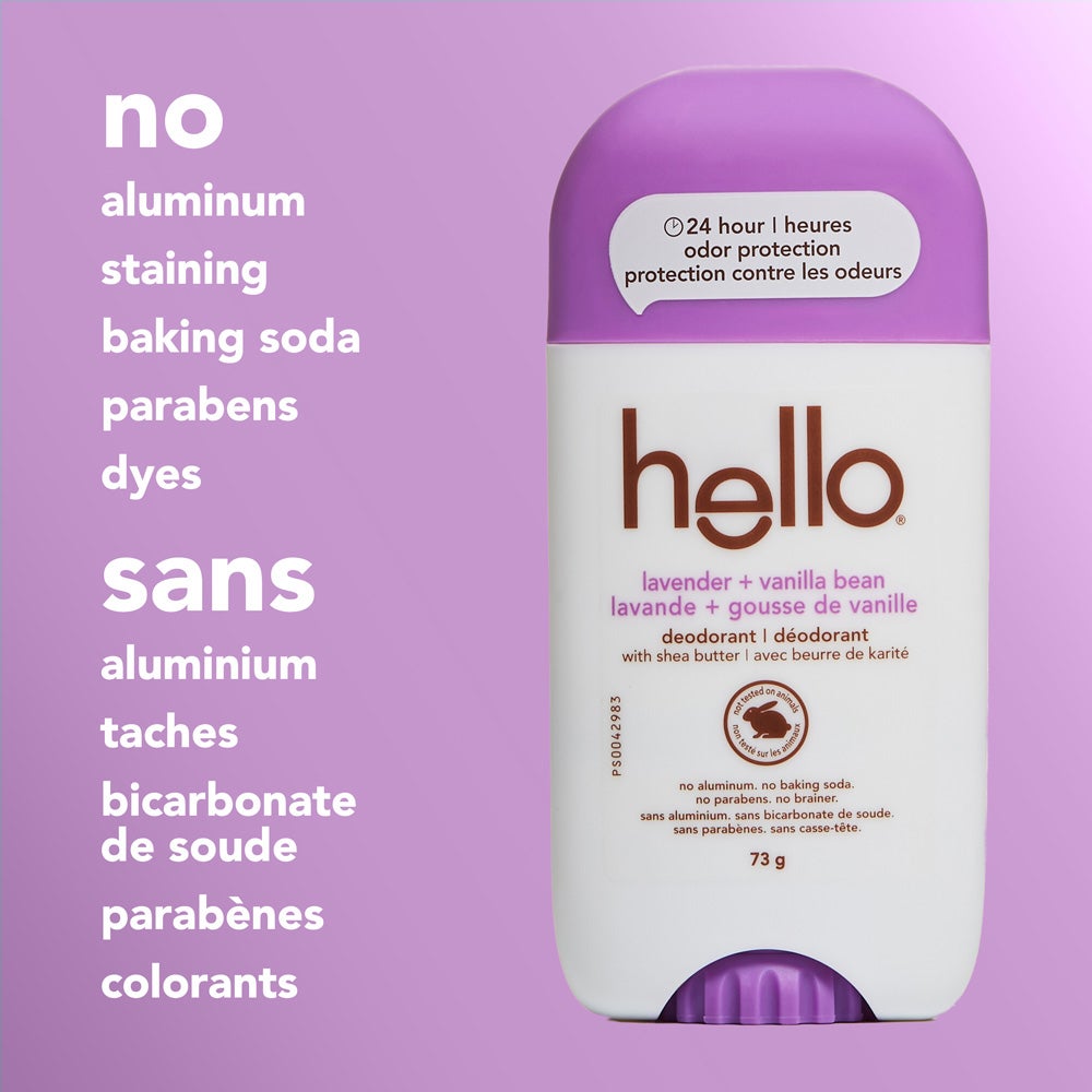 A close-up of a hello Lavender Vanilla Bean deodorant stick with a little purple cap, standing upright on a light purple background. The image features text listing product attributes: &quot;no aluminum, staining, baking soda, parabens, dyes.&quot;