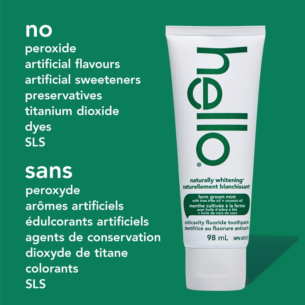 A tube of hello naturally whitening fluoride toothpaste with farm grown mint is displayed upright on a dark green background. Beside the tube, text reads: &quot;no peroxide, artificial flavours, artificial sweeteners, preservatives, titanium dioxide, dyes, SLS&quot; in English and French.